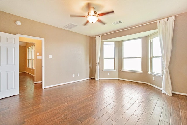 spare room with a ceiling fan, baseboards, visible vents, and wood finished floors