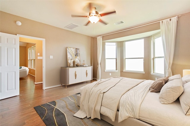 bedroom featuring wood finished floors, visible vents, and multiple windows