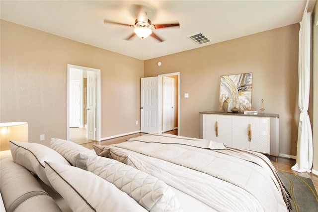 bedroom with ceiling fan, wood finished floors, visible vents, and baseboards