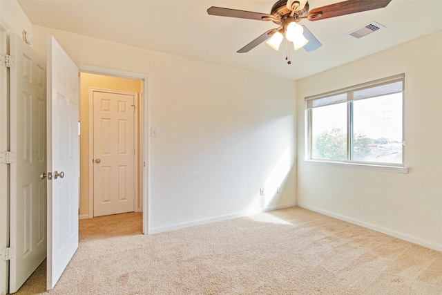 unfurnished room featuring baseboards, visible vents, a ceiling fan, and light colored carpet