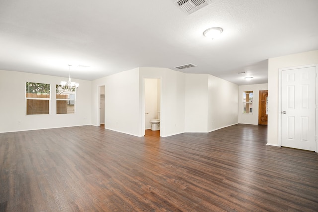 spare room featuring baseboards, visible vents, dark wood-style flooring, and a notable chandelier