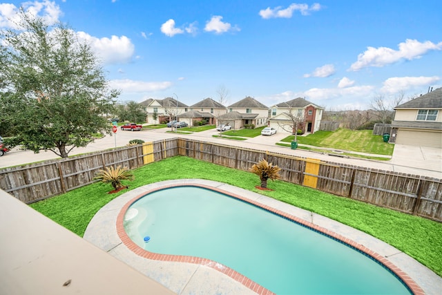 view of pool with a yard, a fenced backyard, and a residential view