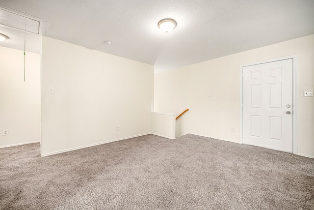 spare room with attic access, carpet, and a textured ceiling