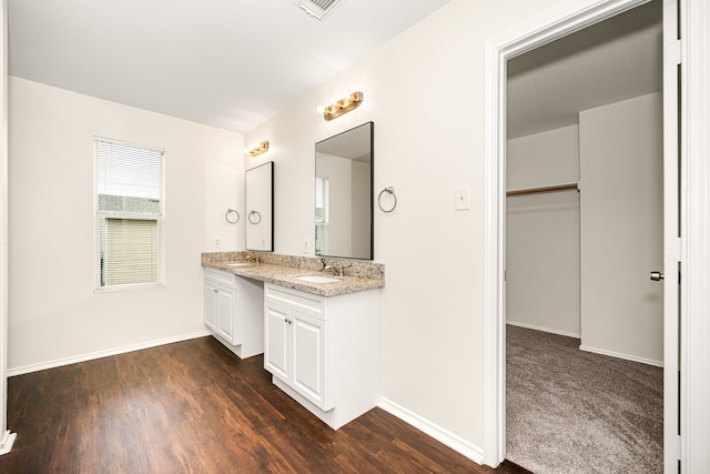 bathroom featuring double vanity, wood finished floors, a sink, and baseboards