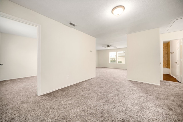 empty room with a textured ceiling, carpet floors, visible vents, and baseboards