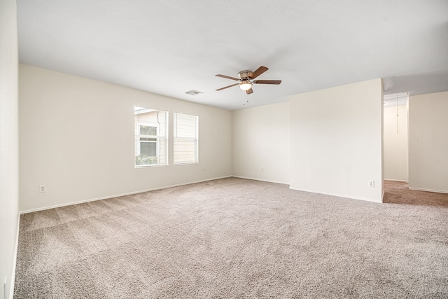 carpeted empty room featuring a ceiling fan, visible vents, and baseboards