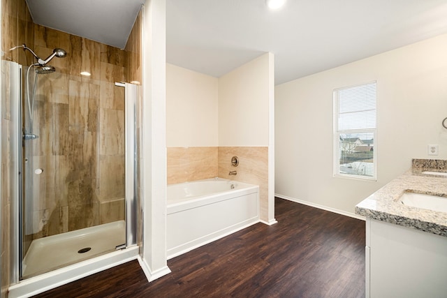 full bath featuring double vanity, a stall shower, wood finished floors, a garden tub, and a sink