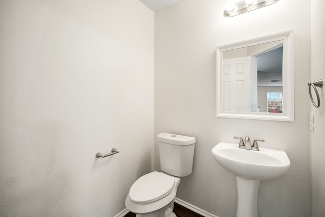 bathroom featuring toilet, baseboards, and a sink