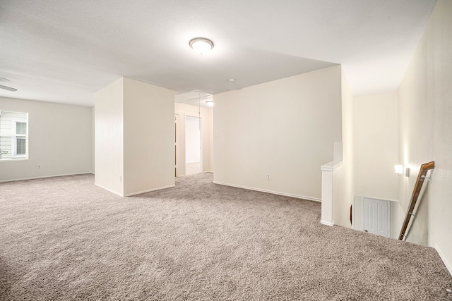 empty room with attic access, baseboards, and carpet flooring