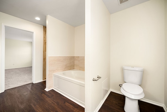 bathroom featuring baseboards, a garden tub, toilet, and wood finished floors