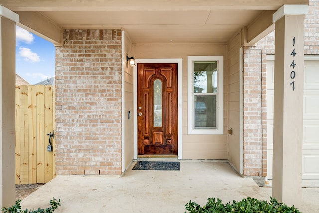 doorway to property featuring a garage and brick siding