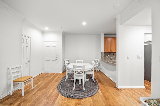 dining room featuring light wood-style floors, baseboards, crown molding, and recessed lighting