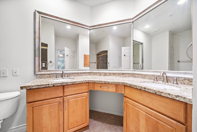 bathroom with double vanity, a sink, and toilet