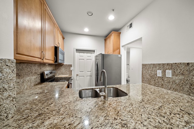 kitchen with light stone countertops, visible vents, stainless steel appliances, and a sink