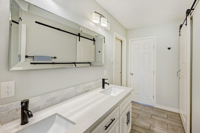 bathroom featuring double vanity, baseboards, a sink, and wood finish floors