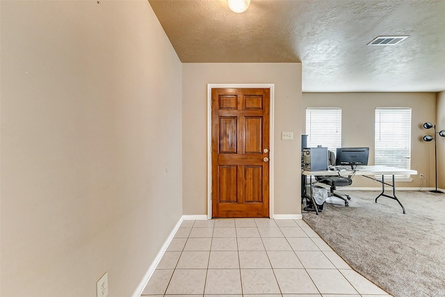 interior space with light carpet, light tile patterned floors, baseboards, and visible vents