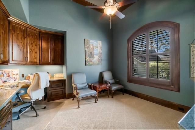 home office featuring light carpet, built in study area, a ceiling fan, and baseboards