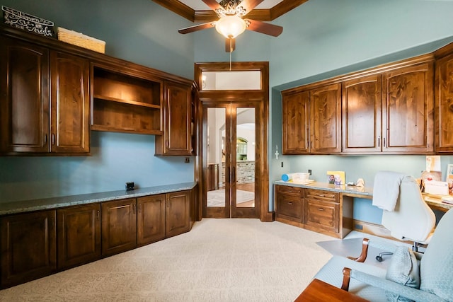 kitchen featuring light carpet, ceiling fan, light countertops, open shelves, and built in desk