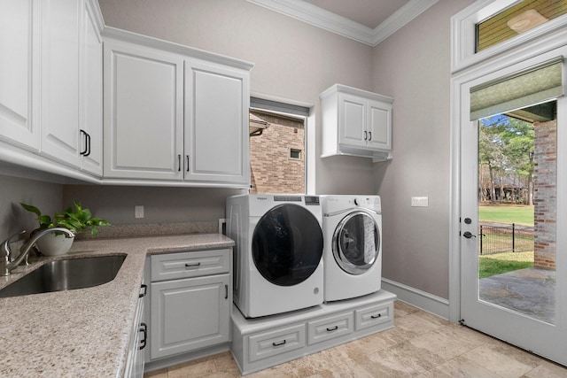 washroom with a sink, baseboards, washer and dryer, cabinet space, and crown molding