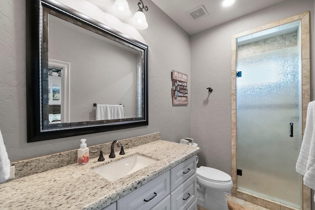 bathroom with toilet, a stall shower, vanity, and visible vents