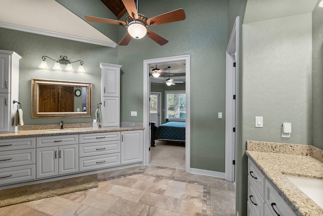 ensuite bathroom with a sink, a textured wall, two vanities, and connected bathroom