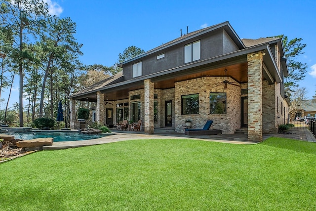 back of property with a ceiling fan, a patio area, and a lawn