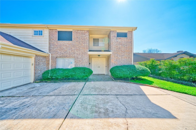 townhome / multi-family property with concrete driveway and brick siding