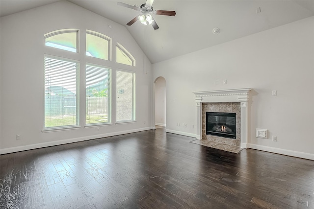 unfurnished living room featuring arched walkways, a ceiling fan, dark wood-style floors, a fireplace, and high vaulted ceiling