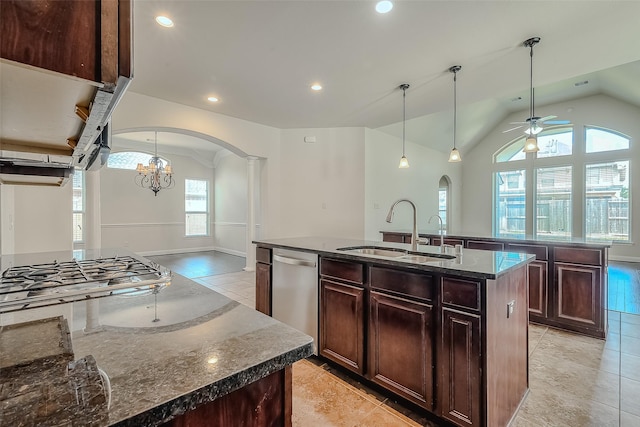 kitchen featuring arched walkways, pendant lighting, stainless steel appliances, a kitchen island with sink, and a sink