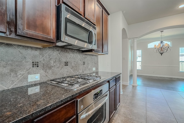 kitchen with light tile patterned floors, arched walkways, decorative backsplash, decorative light fixtures, and stainless steel appliances