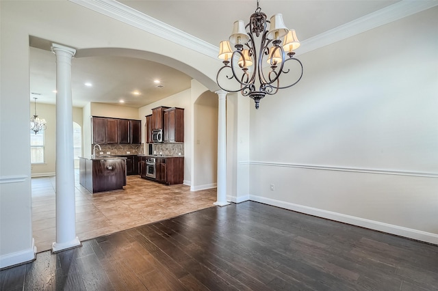 interior space featuring light wood-type flooring, an inviting chandelier, decorative columns, and arched walkways