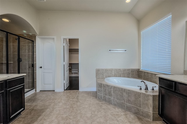 bathroom with tile patterned floors, a walk in closet, vanity, a shower stall, and a bath