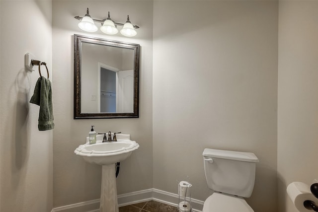 half bathroom featuring tile patterned flooring, toilet, and baseboards