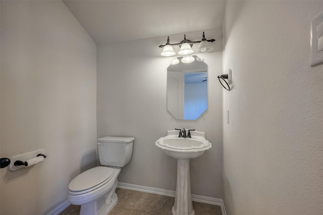 half bath with tile patterned flooring, baseboards, and toilet