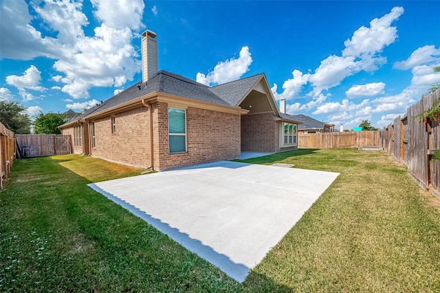 rear view of house with a yard, brick siding, a chimney, and a patio area