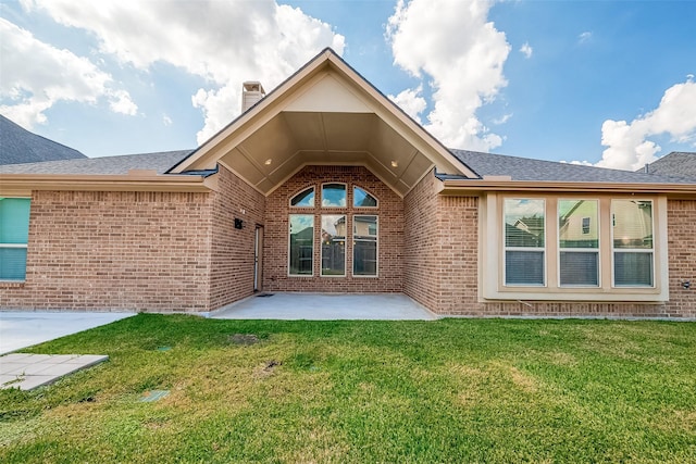 back of house with brick siding, a lawn, and a patio area