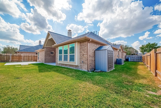 back of house featuring central AC, brick siding, a yard, a shed, and a patio area