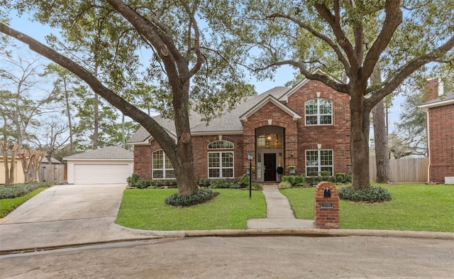 traditional-style home with brick siding, a shingled roof, a front yard, fence, and a garage