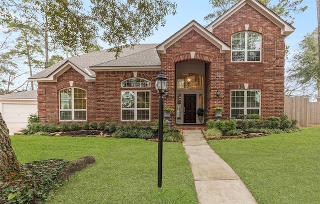 traditional home with a shingled roof, a front yard, and brick siding