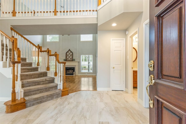 entryway with baseboards, a towering ceiling, stairway, marble finish floor, and a fireplace