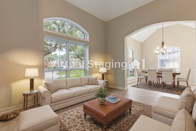 living area with baseboards, arched walkways, a chandelier, crown molding, and high vaulted ceiling