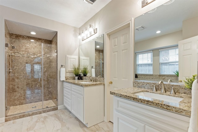 full bathroom featuring marble finish floor, two vanities, a sink, and a stall shower