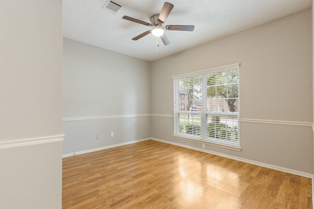 spare room featuring baseboards, a ceiling fan, visible vents, and light wood-style floors