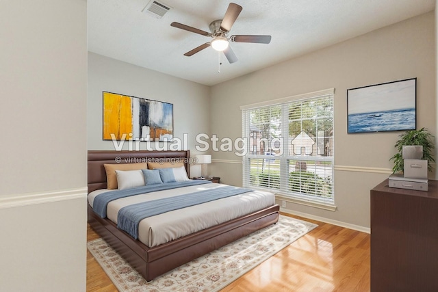 bedroom with light wood-style floors, visible vents, ceiling fan, and baseboards