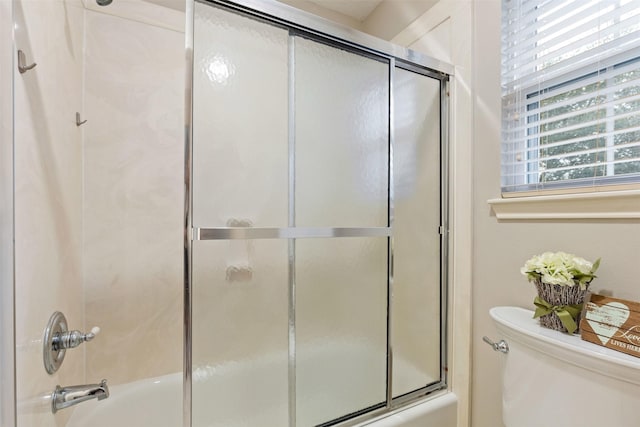 bathroom featuring enclosed tub / shower combo and toilet