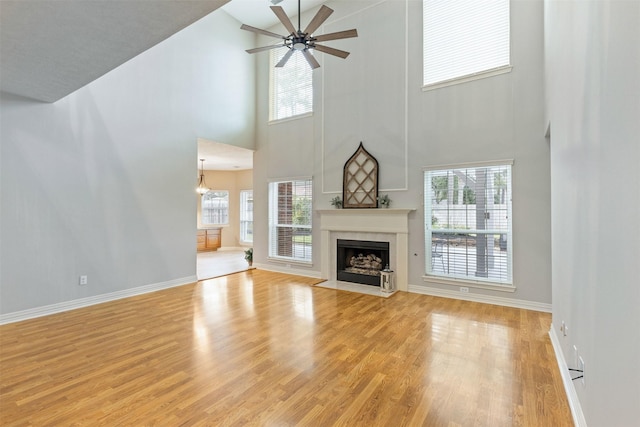 unfurnished living room featuring light wood-type flooring, baseboards, a ceiling fan, and a high end fireplace