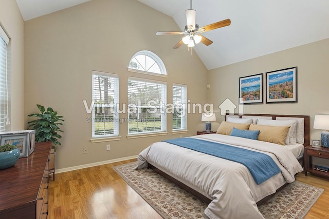 bedroom with ceiling fan, high vaulted ceiling, light wood finished floors, and baseboards