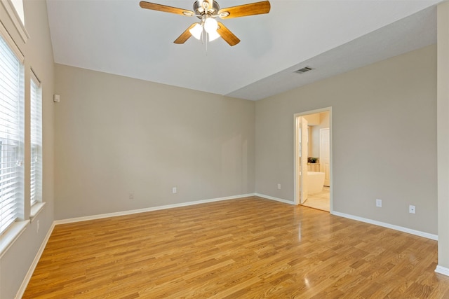 empty room with light wood-style floors, visible vents, baseboards, and a ceiling fan