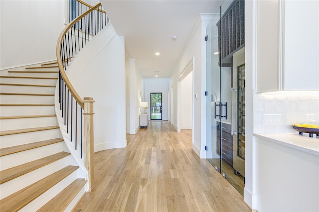 foyer with stairs, recessed lighting, light wood-style flooring, and baseboards