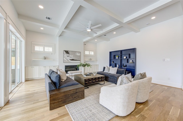 living area with light wood finished floors, beamed ceiling, and visible vents